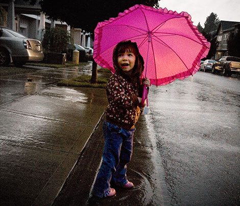Ecstatic to use her new umbrella and boots to splash in the rain.